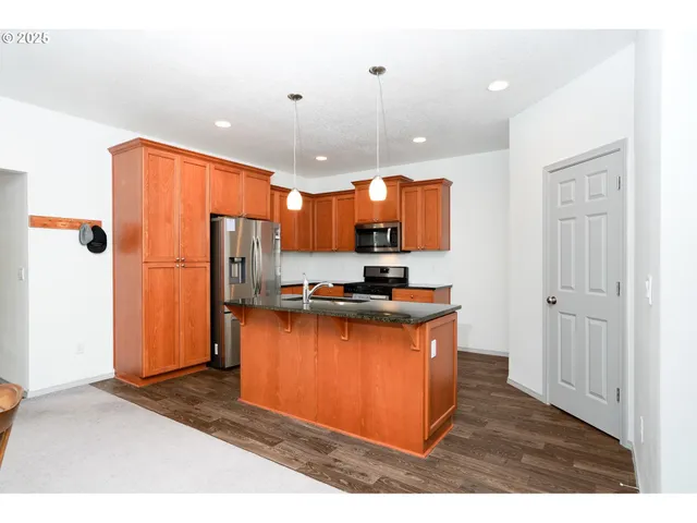 a kitchen with stainless steel appliances granite countertop a refrigerator a sink and a stove