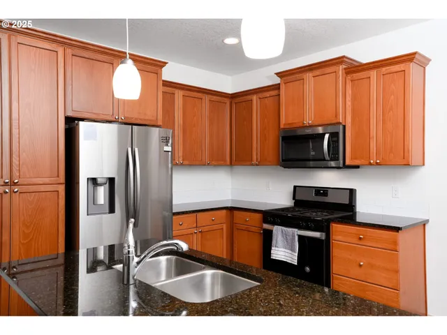 a kitchen with granite countertop a refrigerator stove and microwave