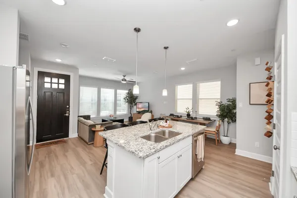 a kitchen with stainless steel appliances granite countertop a stove top oven a sink a dining table and chairs with wooden floor