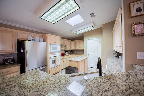 a kitchen with stainless steel appliances kitchen island granite countertop a refrigerator and a stove top oven