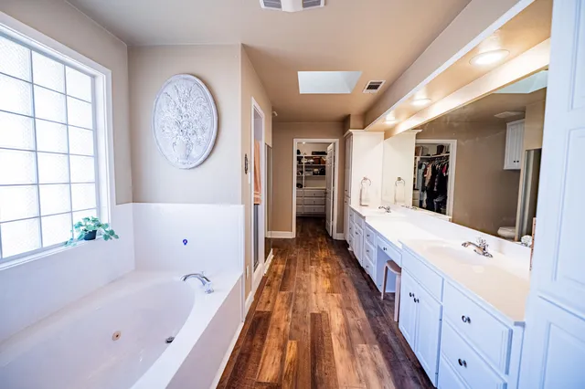 a spacious bathroom with a tub double vanity sink and a large mirror