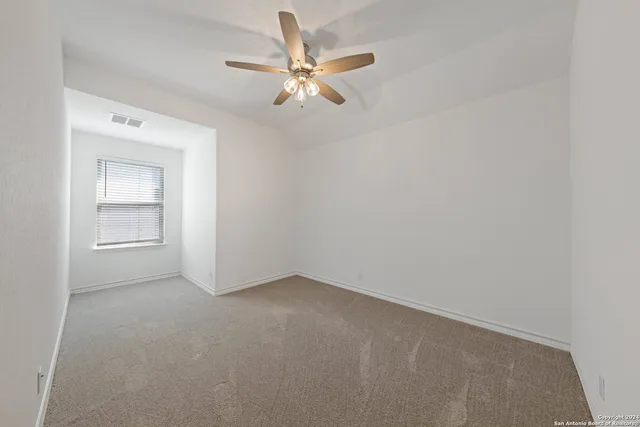 an empty room with a ceiling fan and a window