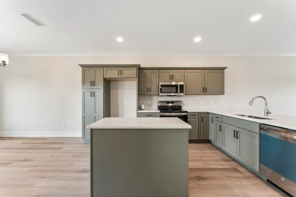 a kitchen with stainless steel appliances a sink dishwasher a stove top oven a refrigerator with wooden floors and cabinets