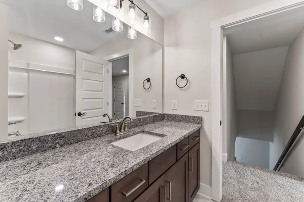 a bathroom with a granite countertop sink a large mirror and a shower