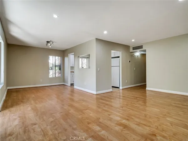 a view of an empty room with window and wooden floor