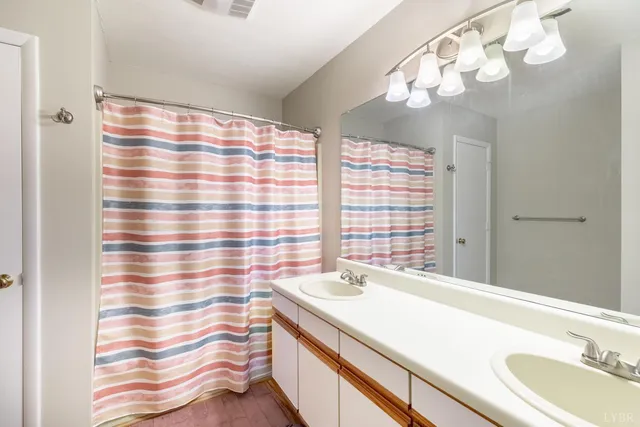 a bathroom with a sink a large mirror and a shower curtain