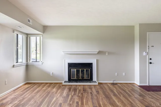 an empty room with windows and fireplace