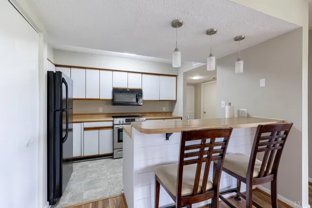 a kitchen with stainless steel appliances granite countertop a kitchen island a stove a table and chairs in it