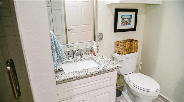 a bathroom with a granite countertop toilet sink and mirror