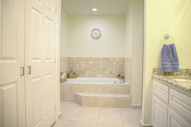 a bathroom with a granite countertop bathtub shower and mirror
