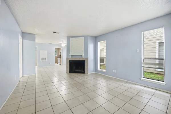 a view of empty room with kitchen and fireplace