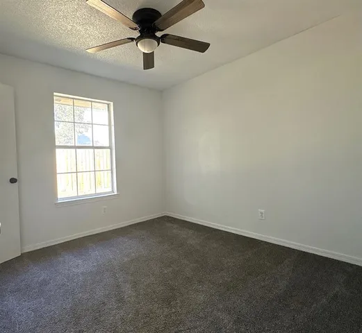 an empty room with a window and a fan