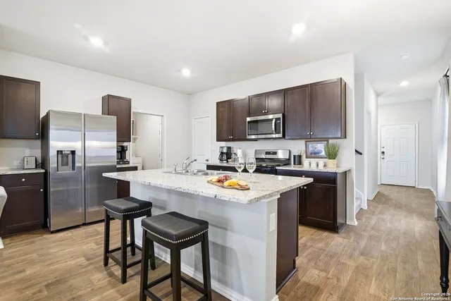 a kitchen with a refrigerator a sink a stove a microwave and chairs