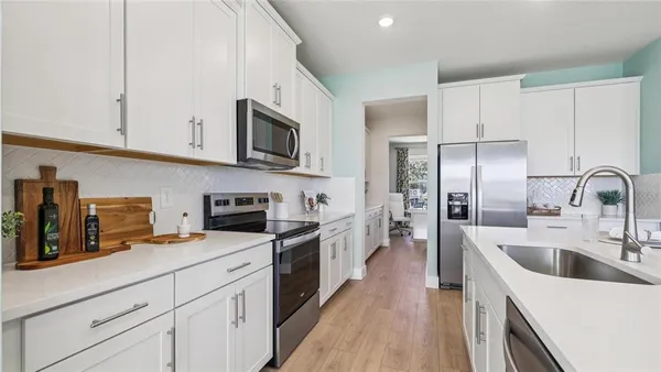 a kitchen with stainless steel appliances a sink a stove top oven a refrigerator a counter space and cabinets