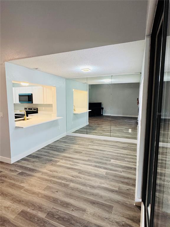 4100 Player Circle, Unit 101 Orlando, FL 32808 - Photo 9 of 34 an empty room with wooden floor and a kitchen