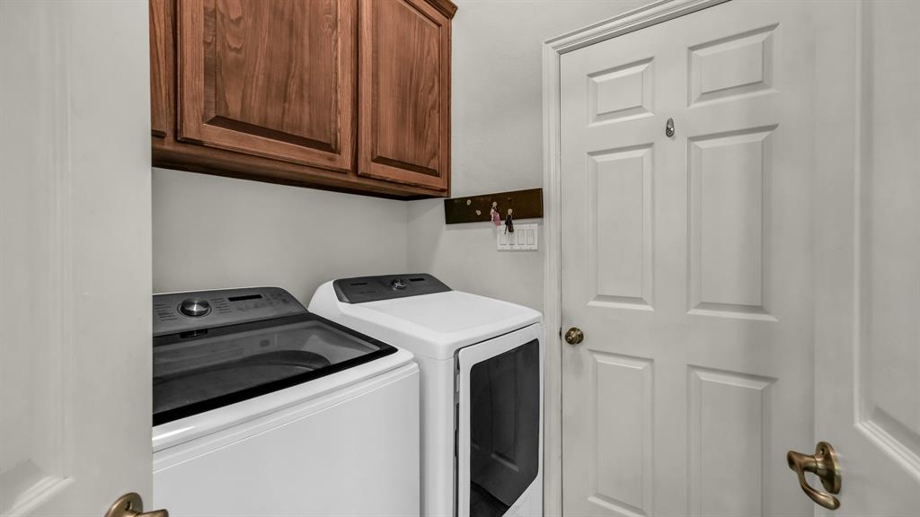203 Mockingbird Lane Aledo, TX 76008 - Photo 21 of 37 Laundry area with upper wood cabinetry and neutral wall finishes