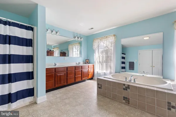 a spacious bathroom with a double vanity sink large mirror and bathtub