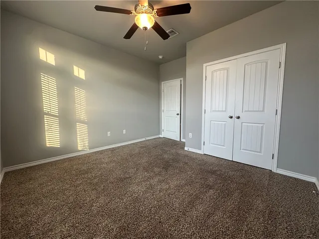 a view of an empty room and chandelier fan