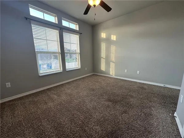 an empty room with chandelier fan and windows