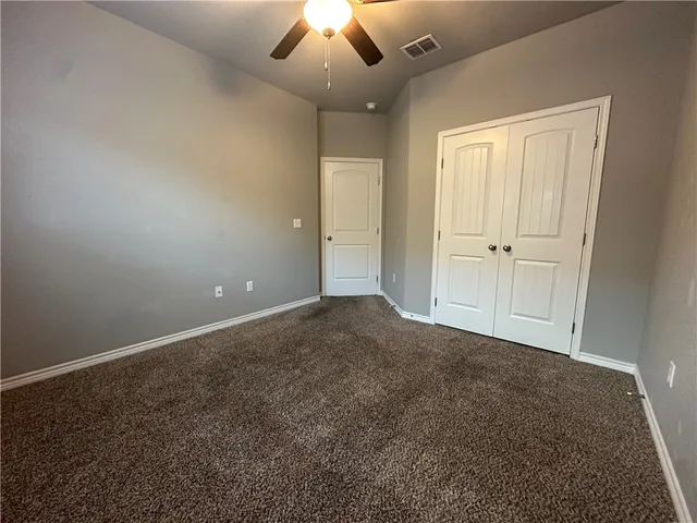 an empty room with a ceiling fan and window