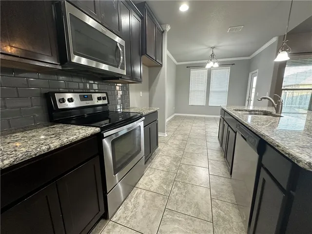 a kitchen with granite countertop a stove a sink and a microwave