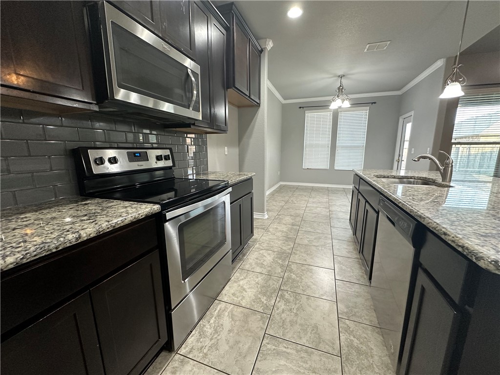 1015 Santa Catalina Street Portland, TX 78374 - Photo 6 of 34 a kitchen with granite countertop a stove a sink and a microwave