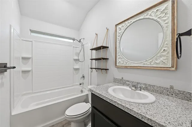 a bathroom with a granite countertop sink toilet and a mirror
