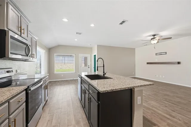 a kitchen with stainless steel appliances granite countertop a sink stove and cabinets