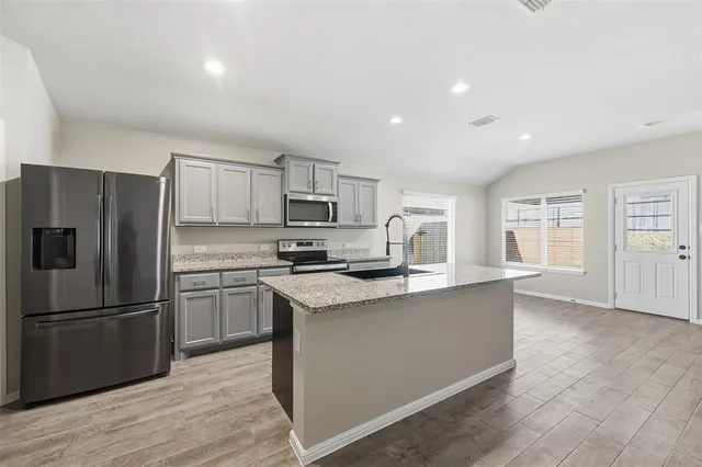 a kitchen with granite countertop a refrigerator and a stove top oven