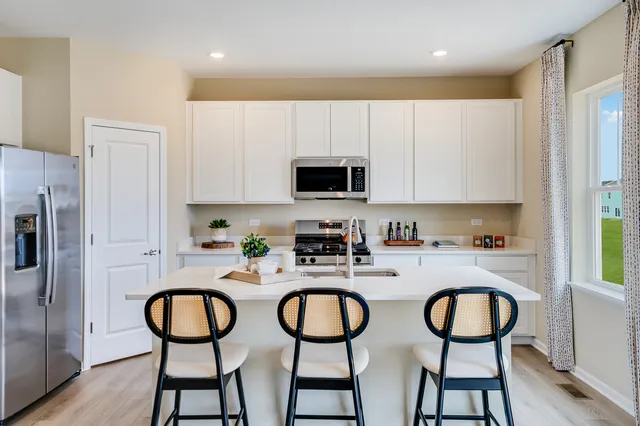 a kitchen with stainless steel appliances a dining table chairs refrigerator and sink