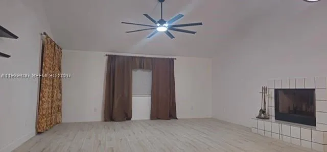 a view of an empty room with wooden floor and a ceiling fan