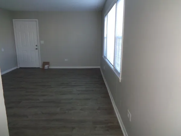 a view of an empty room with wooden floor and window