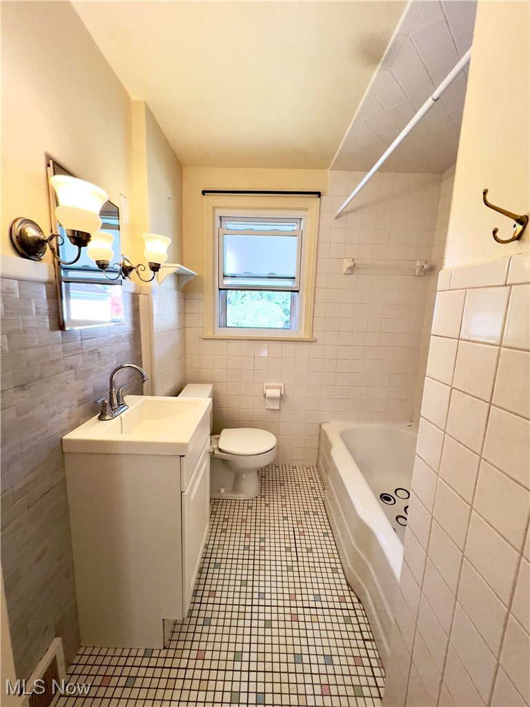 2024 Kirk Road Youngstown, OH 44511 - Photo 15 of 36 Full bathroom with vanity, tile patterned flooring, tile walls, toilet, and tiled shower / bath combo