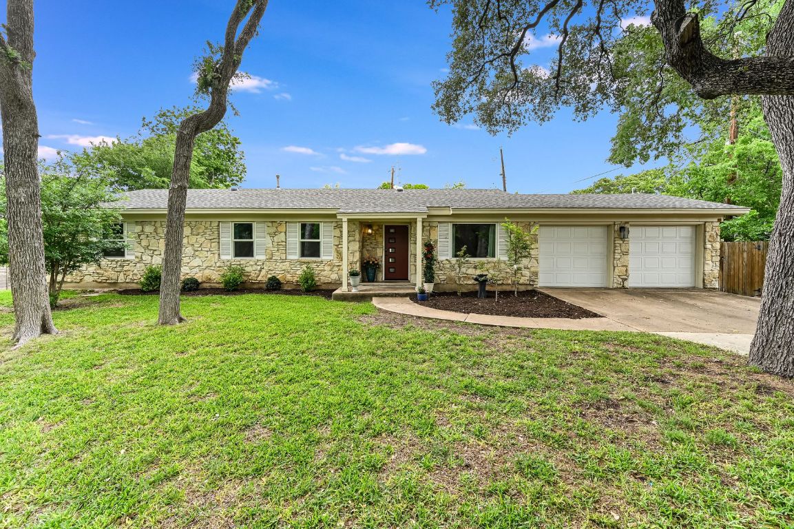 a front view of a house with a garden and trees
