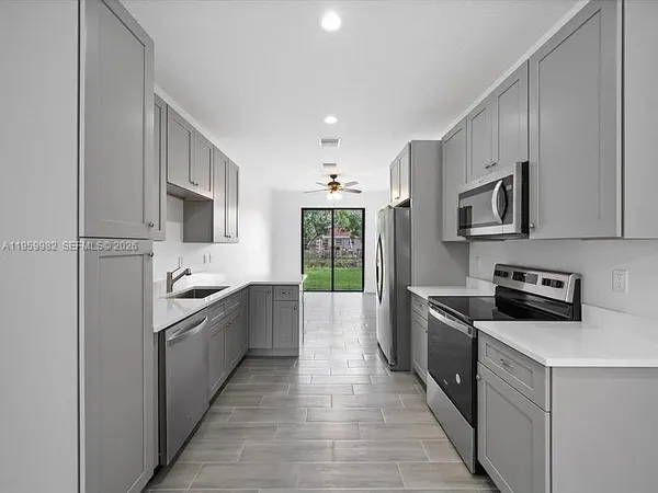 a large kitchen with stainless steel appliances granite countertop a stove top oven a sink dishwasher and a refrigerator