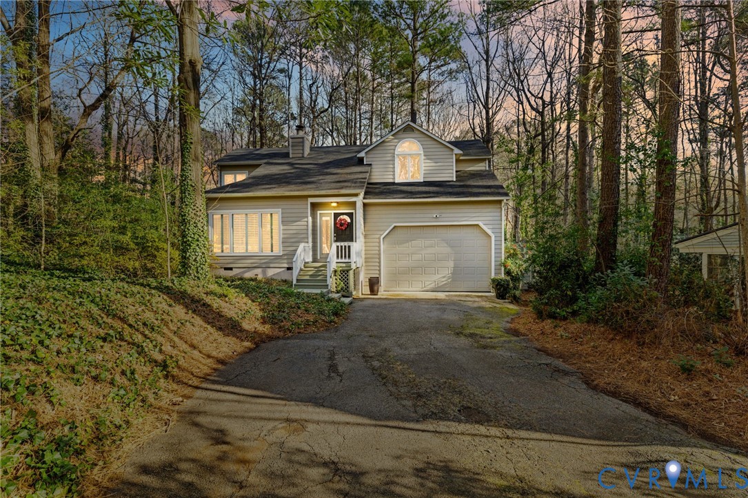 View of front of house featuring asphalt driveway