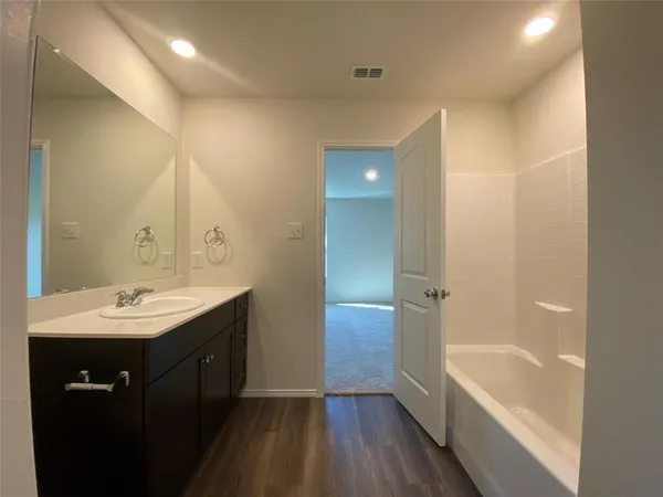 a bathroom with a tub sink shower and two mirror