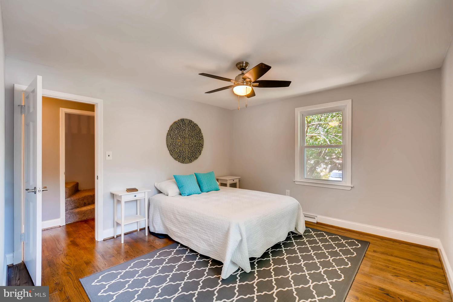 4823 Briarclift Road Baltimore, MD 21229 - Photo 14 of 30 a bedroom with a bed and a table in it with wooden floor