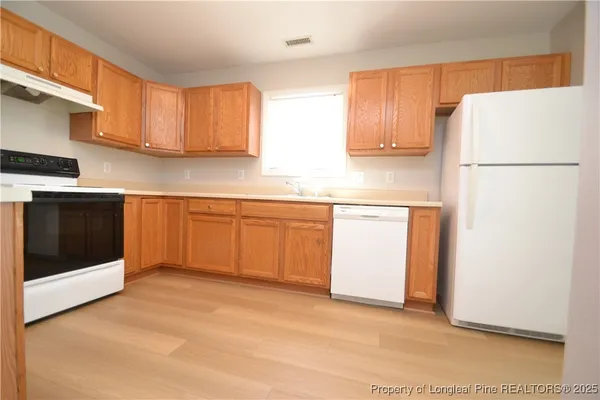 a kitchen with stainless steel appliances granite countertop a refrigerator a sink a stove and white cabinets