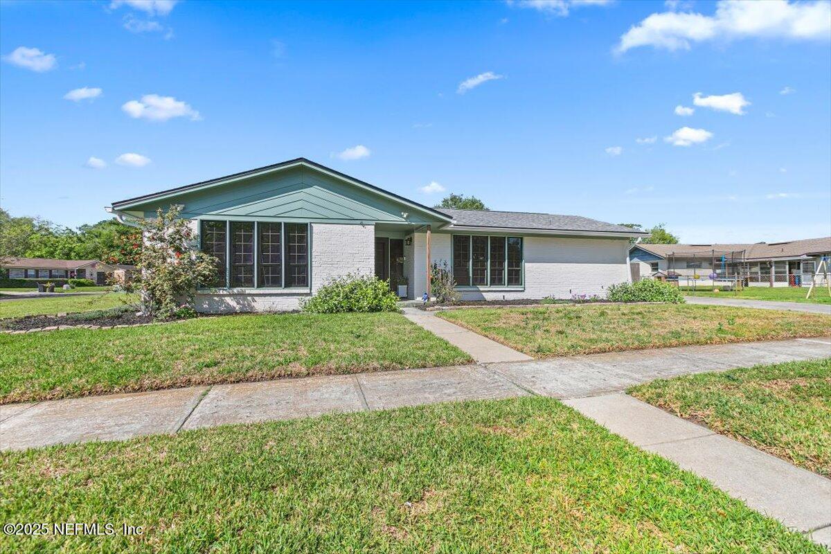 a front view of a house with a yard and potted plants
