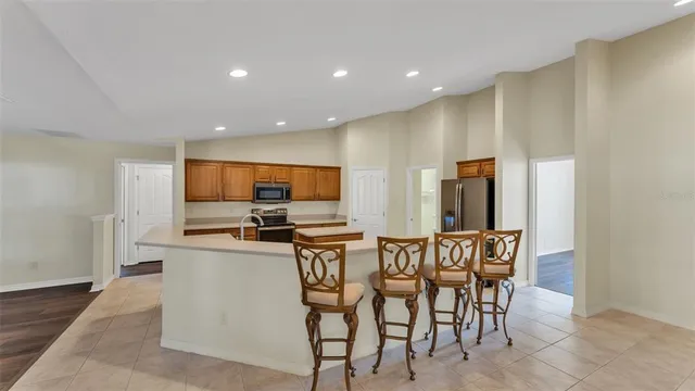 a kitchen with stainless steel appliances a dining table chairs and refrigerator