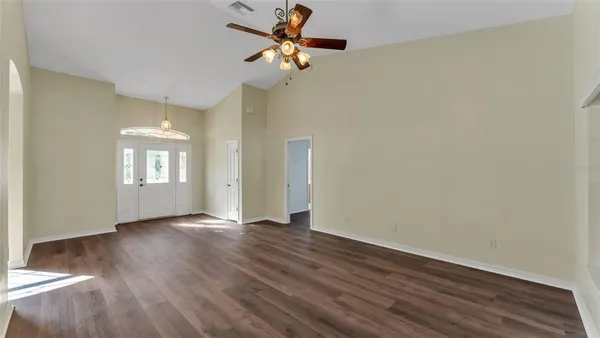 a view of an empty room with a window and wooden floor