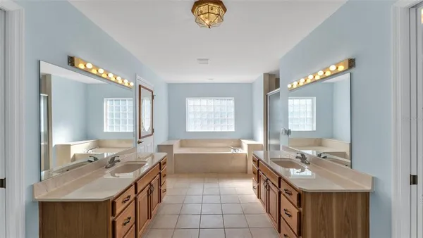 a en suite bathroom with a granite countertop double vanity sink a large mirror and a bathtub