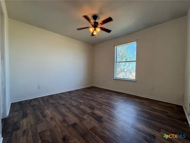 an empty room with ceiling fan and window