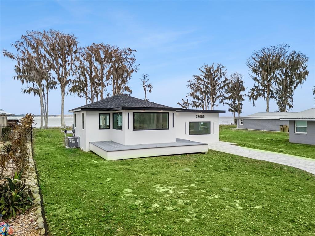 28055 Leuty Road Yalaha, FL 34797 - Photo 27 of 39 a front view of a house with a garden and trees