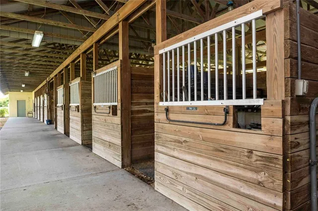 a white kitchen with stainless steel appliances granite countertop a dining table and chairs a refrigerator with wooden cabinets