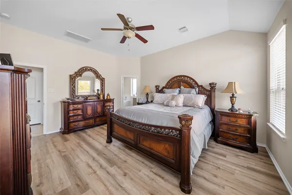 a spacious bedroom with a bed a dresser and a window