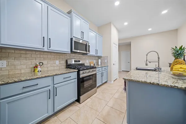 a kitchen with granite countertop a sink stainless steel appliances and cabinets