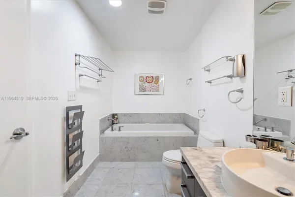 a bathroom with a tub a sink and a large mirror