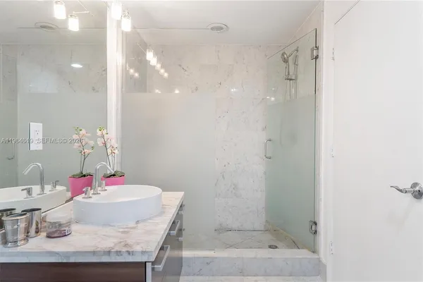 a bathroom with a granite countertop shower a mirror and vanity